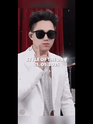 a young man in a white suit and sunglasses is giving a thumbs up .