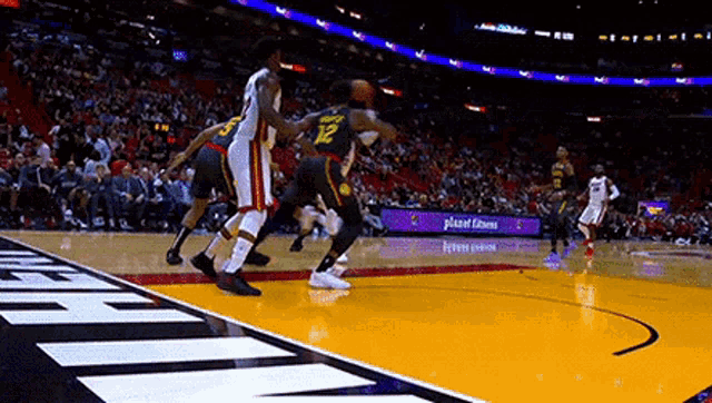 a group of basketball players are playing a game of basketball on a court in front of a crowd .