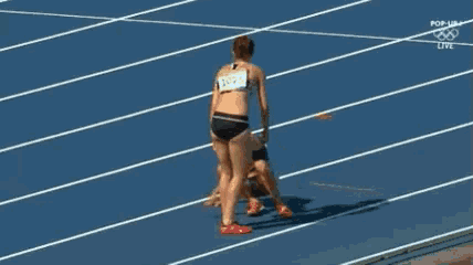 a woman with the number 4025 on her back is standing on top of a man on a track .