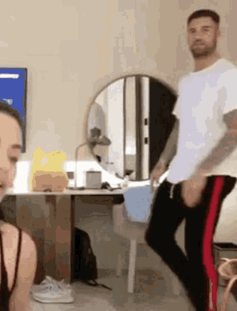 a man in a white shirt and red pants is dancing in a room .