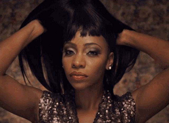 a woman in a sequined top is holding her hair in her hands