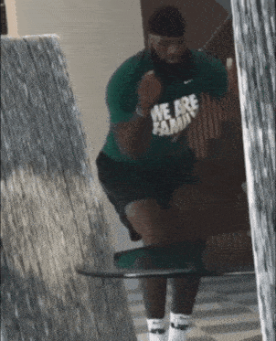 a man in a green shirt that says we are family jumps in the air