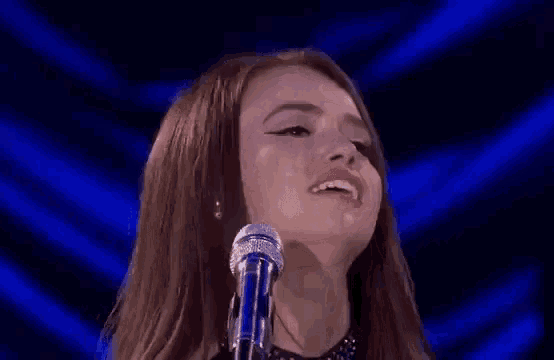a woman is making a funny face while singing into a microphone .