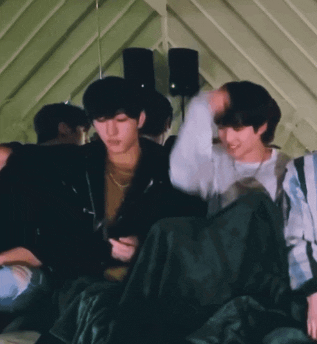 two young men are hugging each other while laying on a bed .
