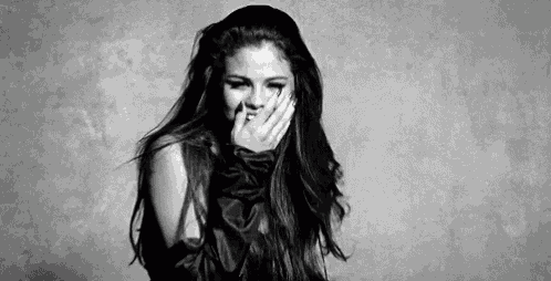 a black and white photo of a woman covering her mouth with her hands .