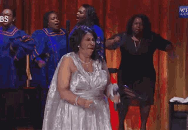 a woman in a white dress is singing into a microphone on a stage