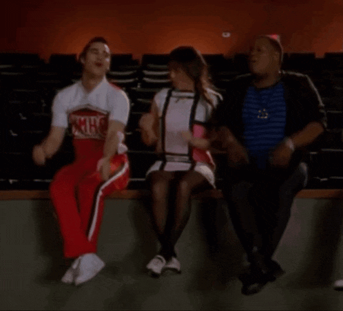 a man in a cheerleader outfit is sitting next to a woman