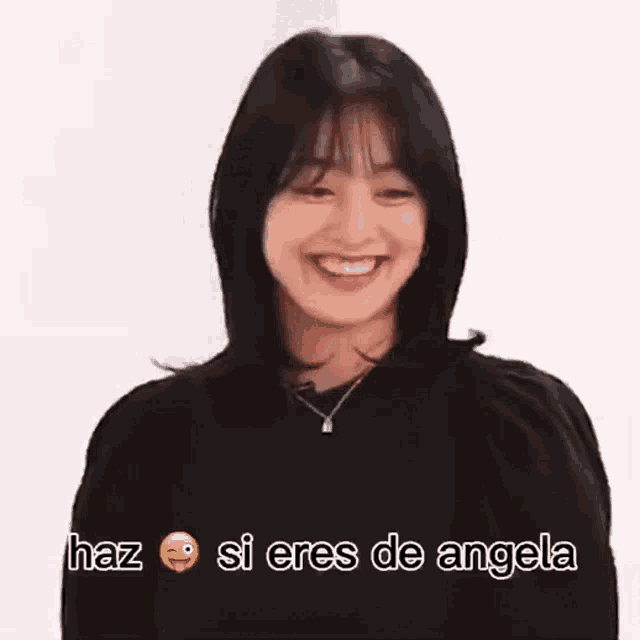 a woman wearing a black sweater and a necklace is smiling and saying haz si eres de angela .