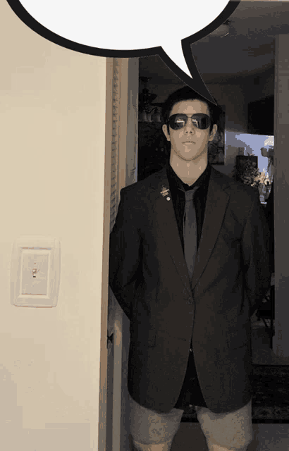 a man in a suit and tie stands in a doorway with a speech bubble above him