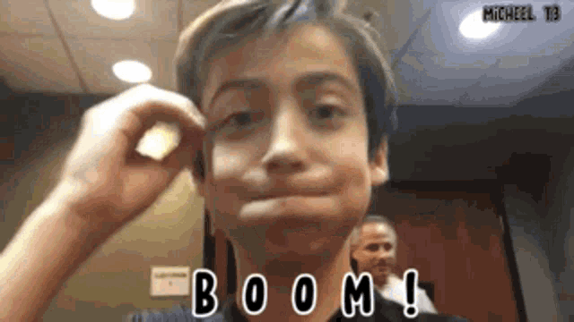 a young boy is making a funny face in a room with the words boom written on the bottom .