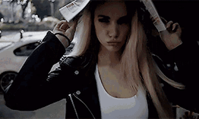a woman wearing a black leather jacket and a white tank top