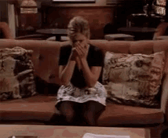 a woman is sitting on a couch with her hands over her face .