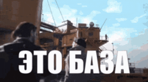 a man is standing in front of a large building with the words " это база " written on it