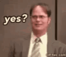 a man in a suit and tie is standing in front of a wall and says yes .