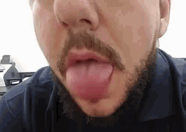a man with a beard sticking his tongue out .
