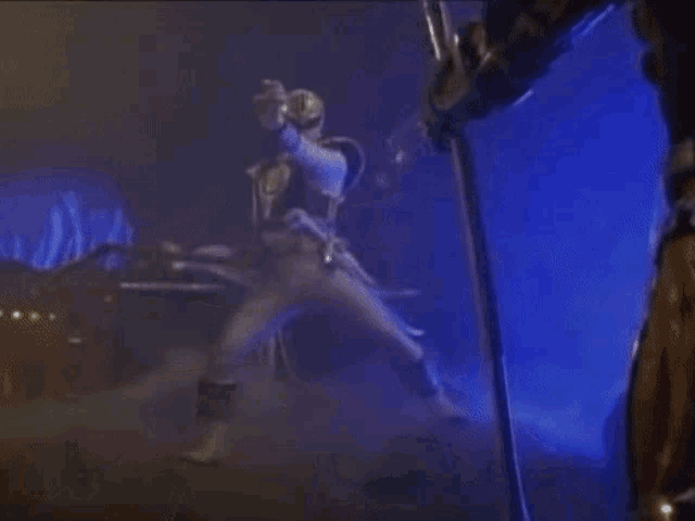 a man in a costume is standing in a dark room with a sword .