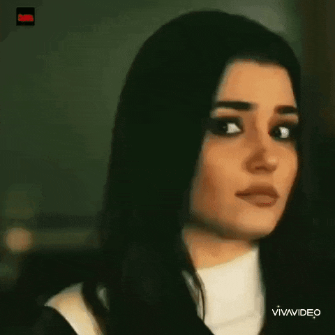 a close up of a woman 's face with long black hair and a white shirt .