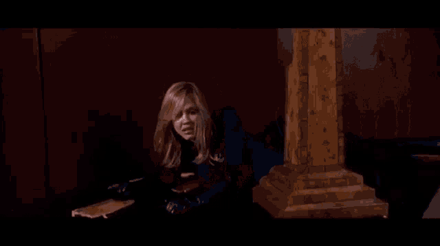 a woman in a blue suit is laying on her stomach in a dark room and looking at the camera .
