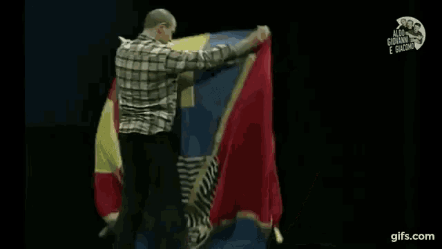 a man in a plaid shirt is holding a large flag in his hands .