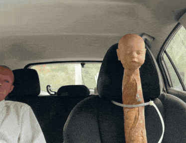 a mannequin with a bread sticking out of it 's head sits in a car