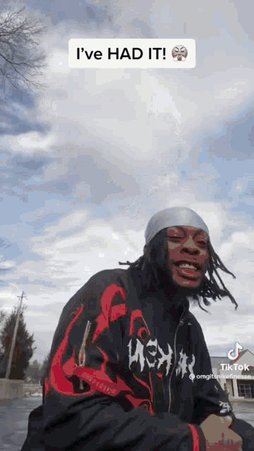 a man with dreadlocks and a bandana on his head is standing in front of a cloudy sky .
