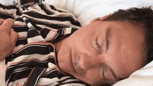 a man in a striped shirt is sleeping on a bed