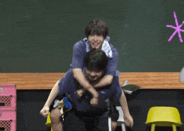 a man is carrying another man on his back in front of a chalkboard