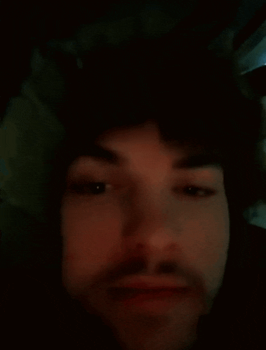 a close up of a man 's face with his eyes closed and a beard