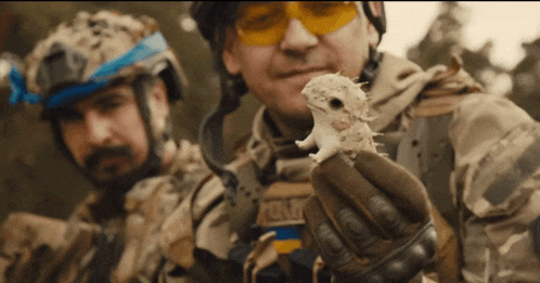 a man in a military uniform is holding a small animal with the word army on it