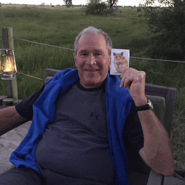 a man wearing a blue under armour shirt holds a picture of a hamster