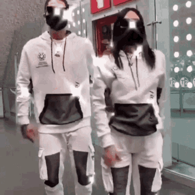 a man and a woman wearing masks and sunglasses are standing next to each other .