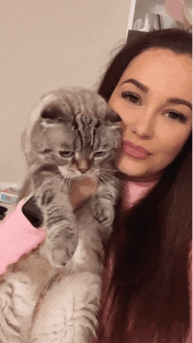 a woman is holding a cat in her arms