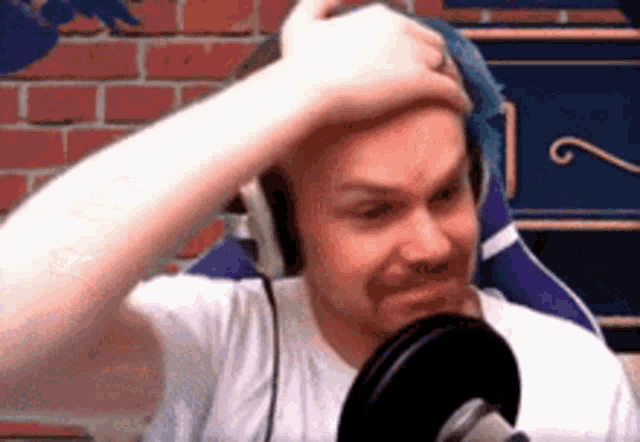 a man wearing headphones is sitting in front of a microphone .