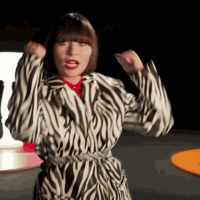 a woman wearing a zebra print coat is dancing
