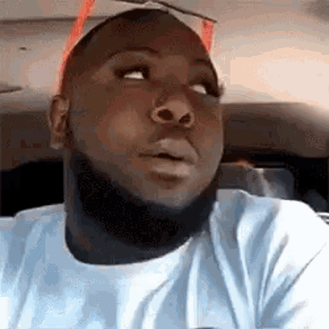 a man with a beard is sitting in a car with his eyes closed and his mouth open .