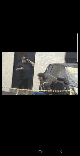 a man is pushing a black car behind a yellow fence .