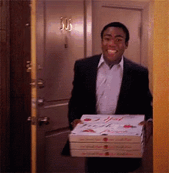 a man in a suit is carrying three boxes of pizza ..