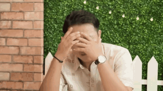 a man wearing a watch is covering his face