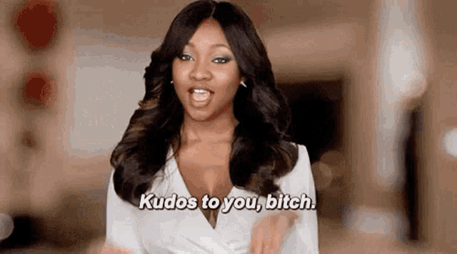 a woman in a white shirt is screaming and saying kudos to you bitch .
