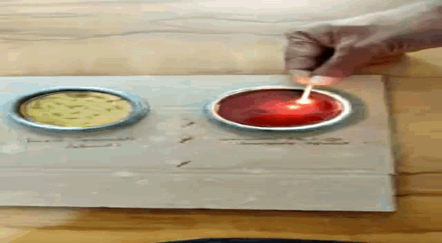 a person is lighting a red candle with a lighter on a cardboard box .