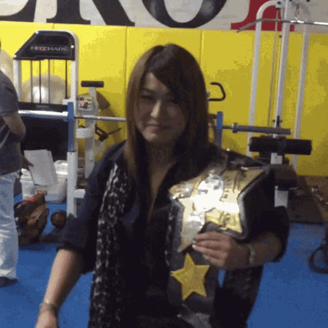 a woman in a gym holding a belt that says prochain on it