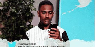 a man is looking at his phone in front of a twitter logo .