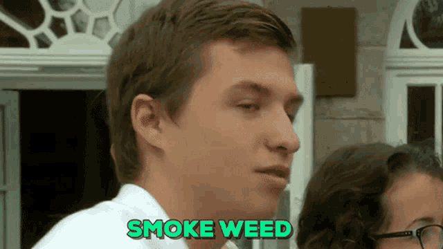a man in a white shirt says smoke weed next to a woman in glasses