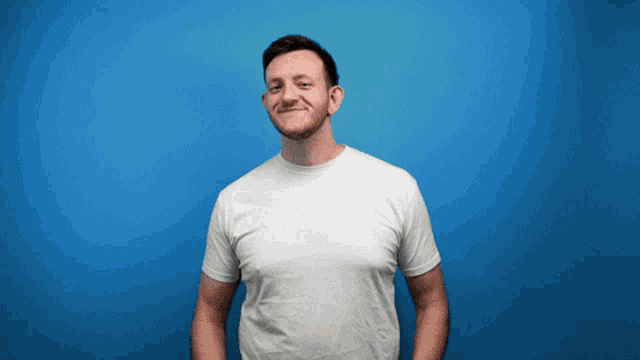 a man in a white t-shirt is smiling in front of a blue background