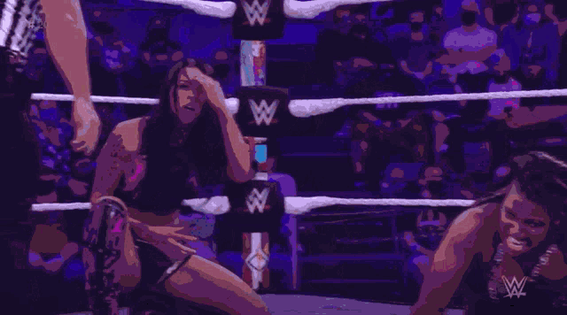 a woman is kneeling down in a wrestling ring with a w logo