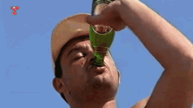 a man wearing a hard hat is drinking from a bottle .