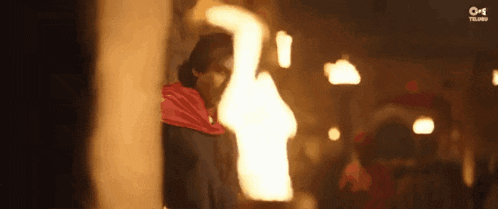 a man in a red cape is holding a torch in his hand in a dark room .