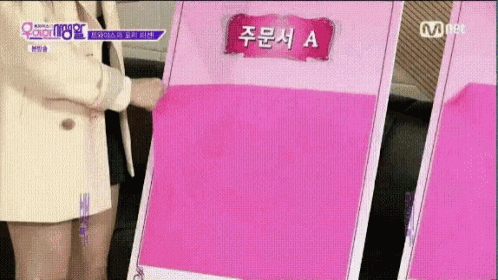 a woman in a white jacket is holding a pink sign that says a .