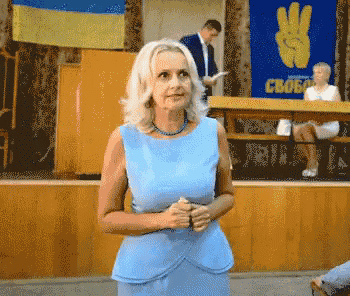 a woman in a blue dress is standing in front of a sign that says свобода