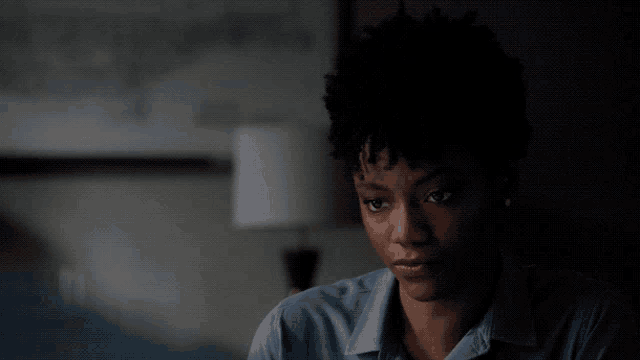 a woman in a blue shirt is sitting in the dark